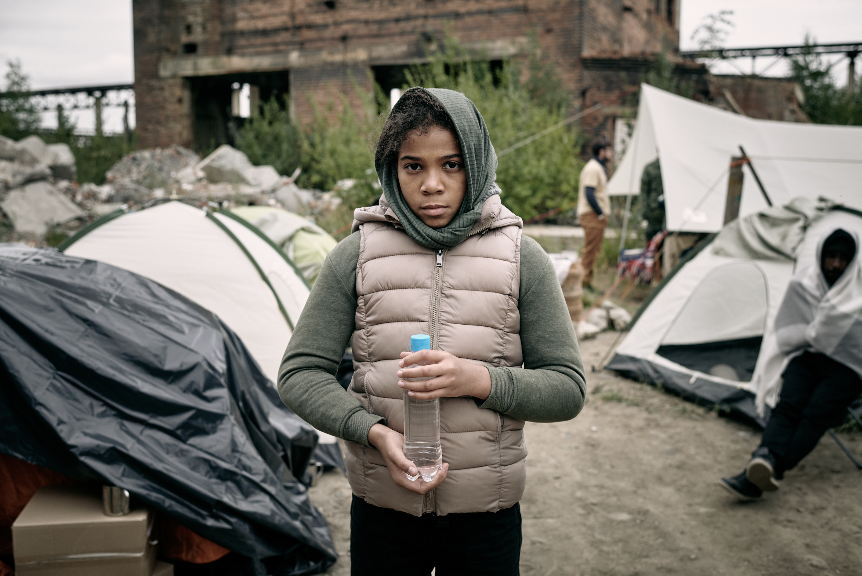 Young refugee holding water bottle in camp