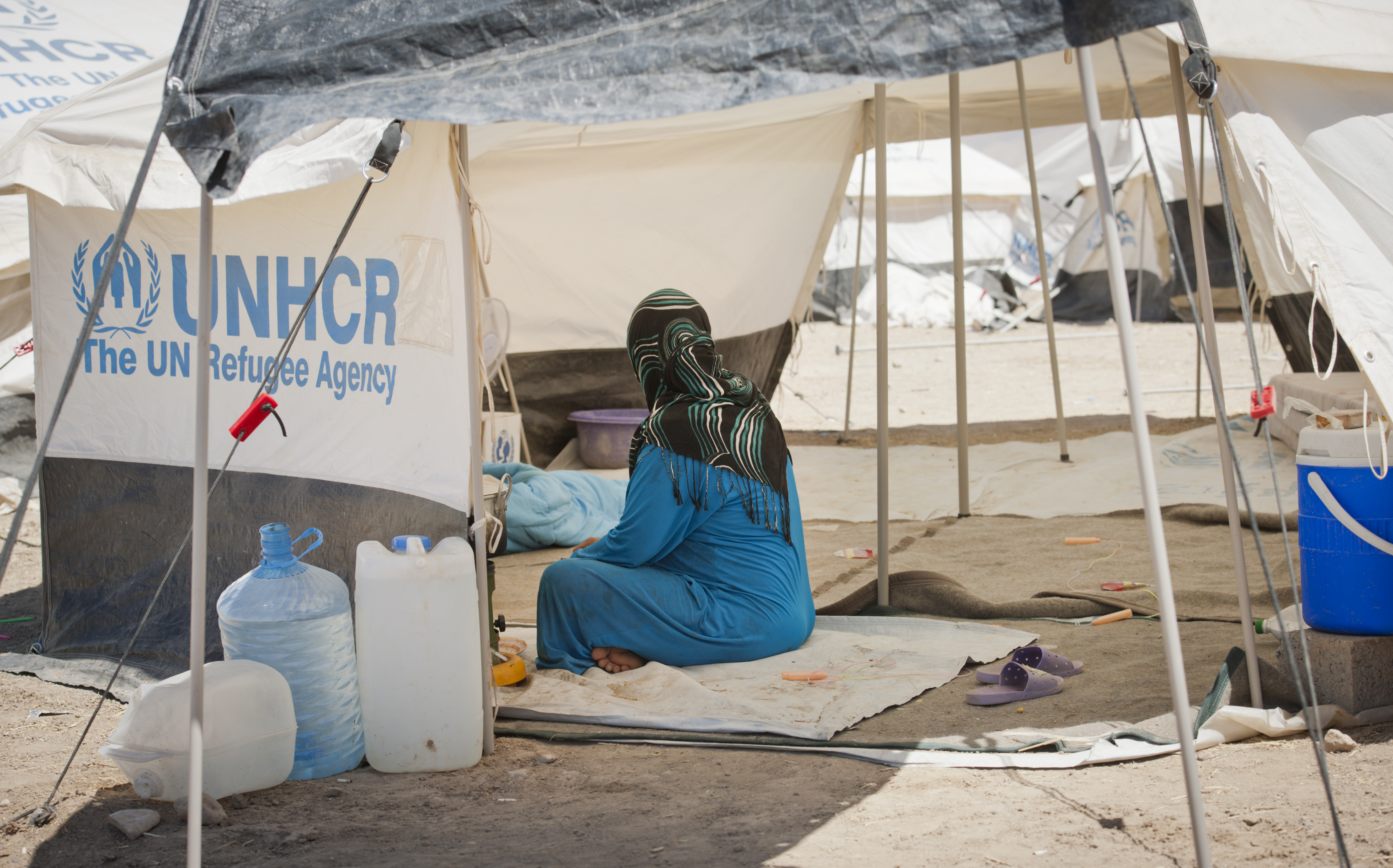 Woman in UNHCR refugee camp with water containers